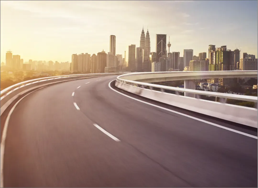 A modern highway leading to a vibrant city skyline at sunrise