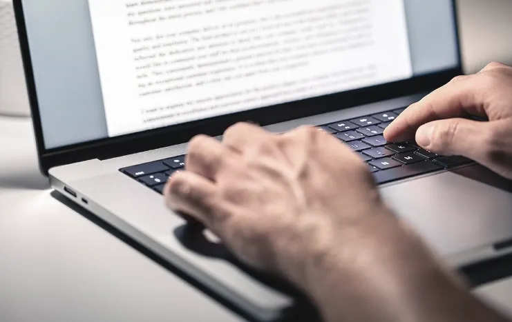 Close-up of hands typing on a laptop keyboard