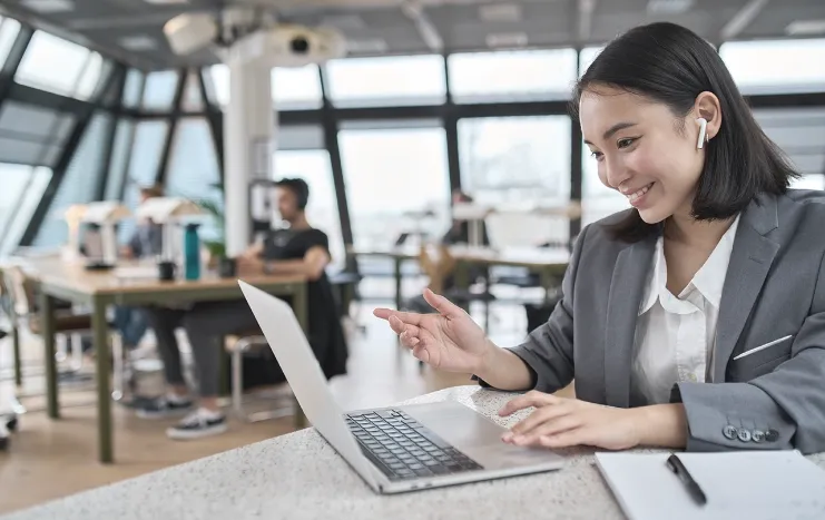 A professional woman using a laptop in a shared workspace
