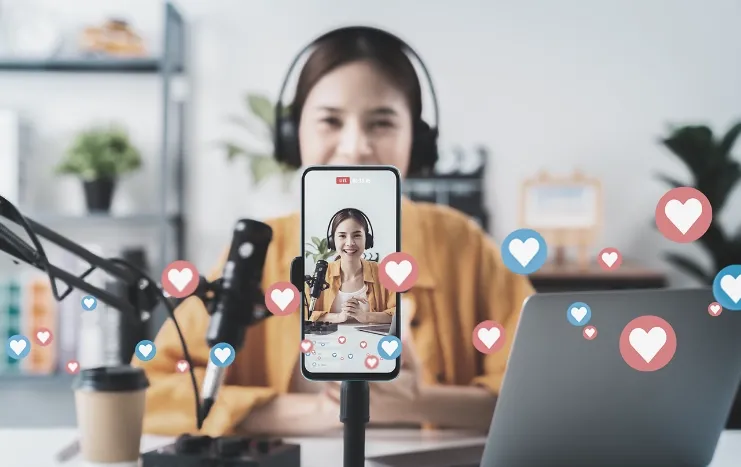 Content creator live streaming in front of a smartphone, with heart and like icons