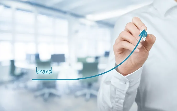 A professional drawing an upward trend line labeled "brand" symbolizing Trinergy's