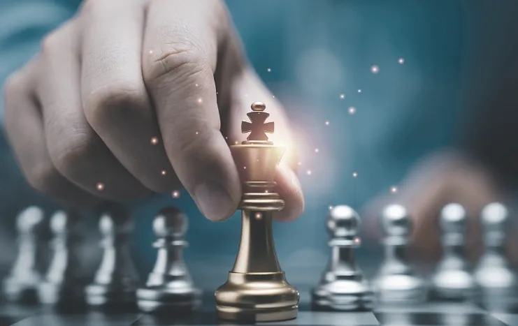 A hand moving a golden chess piece on a chessboard