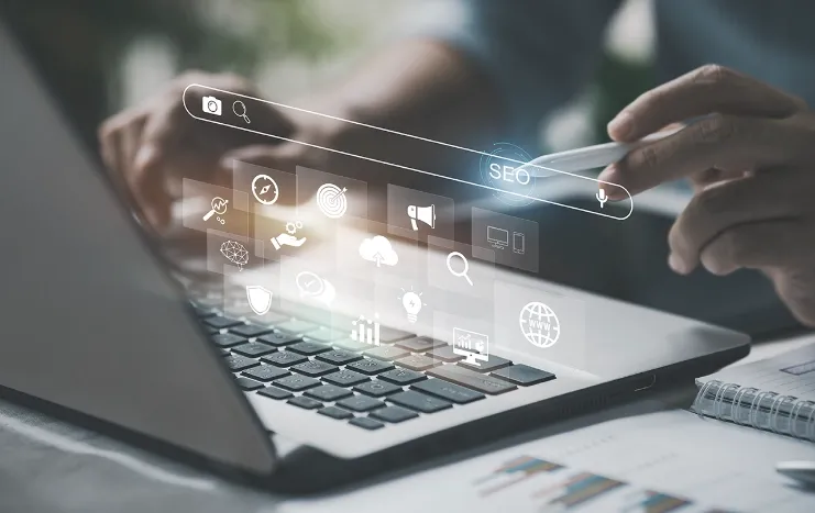 Person using a laptop with digital SEO icons and search bar