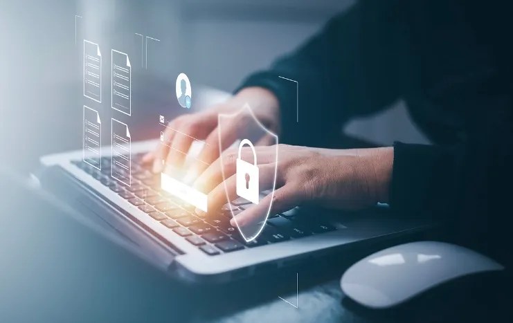 Cybersecurity concept by Trinergy showing a person typing on a laptop with data protection icons