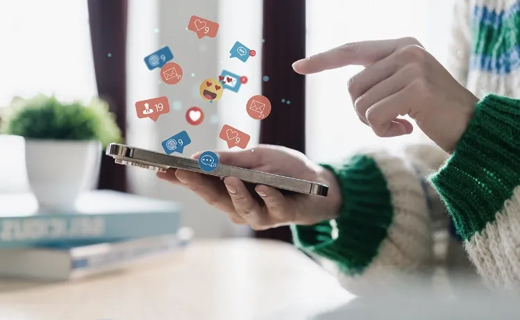 A person interacting with a smartphone, with floating social media icons representing likes, shares