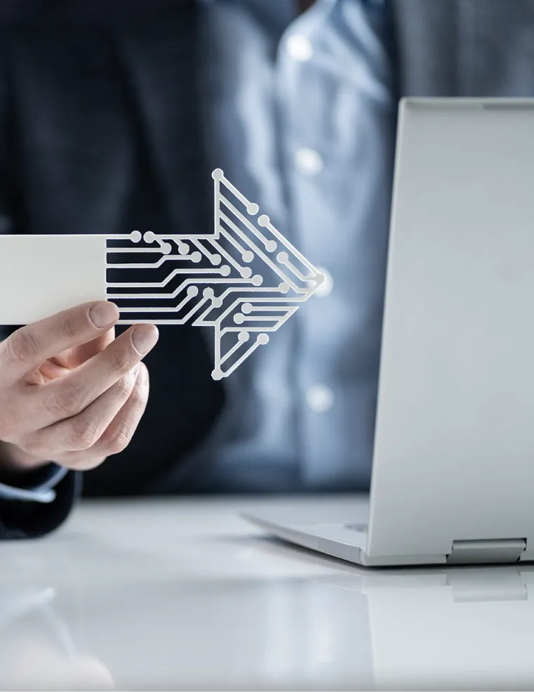 A professional holding a futuristic circuit-like arrow symbol next to a laptop