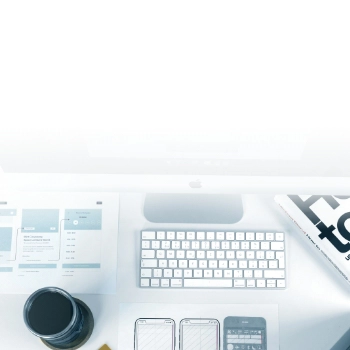 Top view of a digital workspace with keyboard, camera lens, and UI design mockups on desk